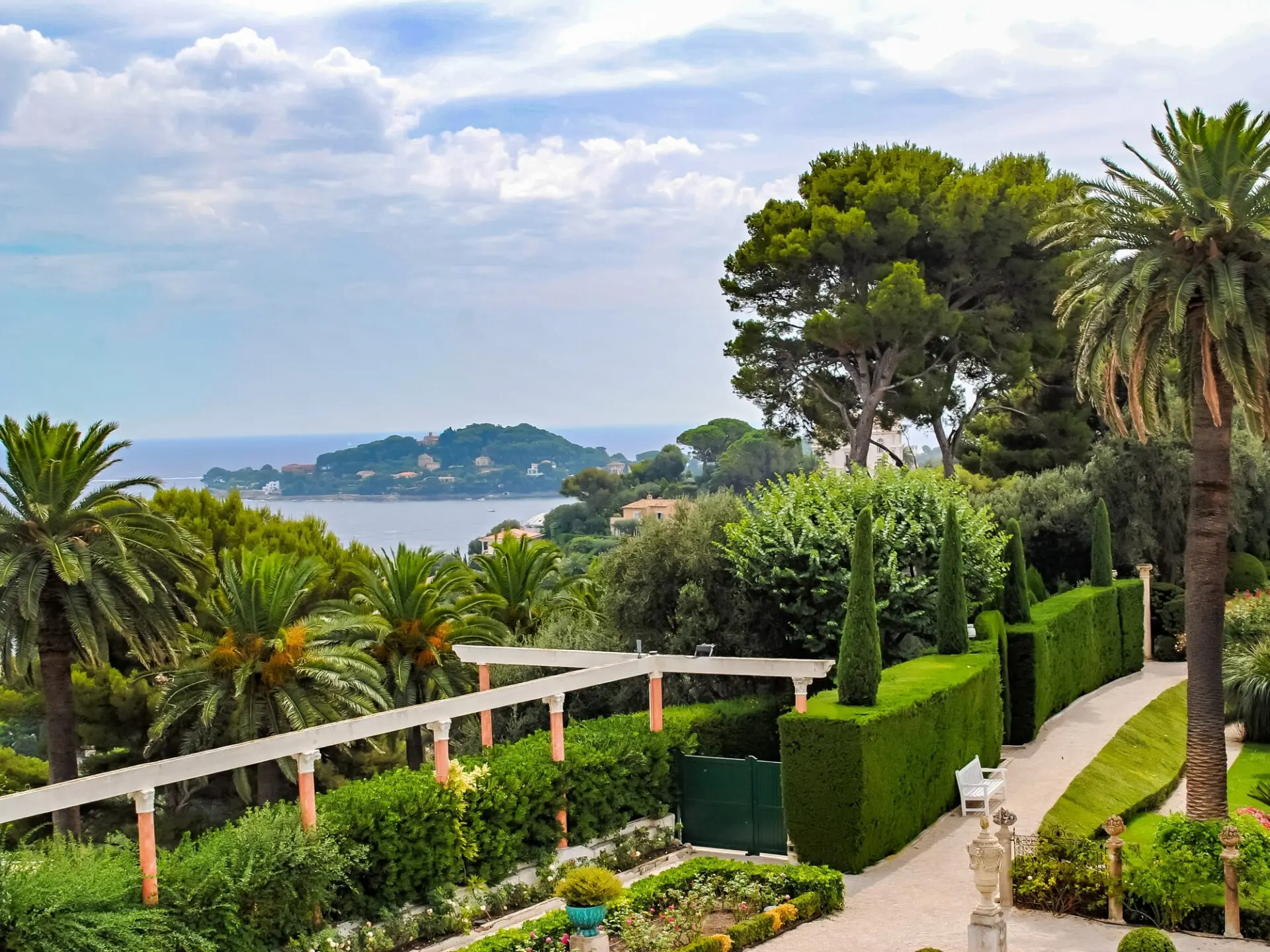L'Art de la Taille : Arbres et Arbustes en Provence 2 Jardin méditerranéen avec haies taillées et palmiers, vue sur la mer en Provence